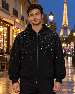 Homme portant le sweat zippé à strass EYDIZ noir devant la tour Eiffel, de nuit